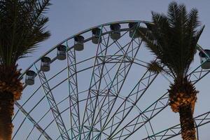 A ferris wheel with a clock tower in the background photo