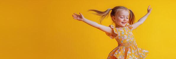 Cheerful child in a yellow floral dress dancing joyfully against a bright yellow background photo