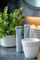 Two blue grooming tools beside a potted plant and a white bowl in a cozy bathroom setting photo