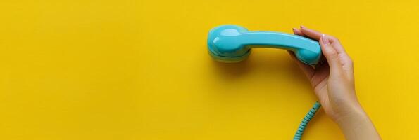 A vibrant blue telephone receiver held against a bright yellow background in a playful setting photo