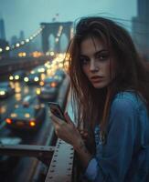 Young woman enjoying the evening view of the Brooklyn Bridge while holding a phone photo