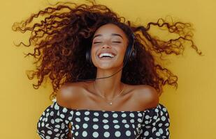 Young woman enjoying music with headphones while smiling against a vibrant yellow background photo