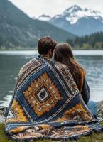 A couple enjoys a relaxing moment by the serene lake surrounded by majestic mountains in nature photo