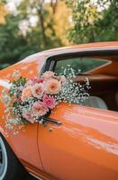 A vintage orange car adorned with colorful flowers parked in a lush green setting during golden hour photo