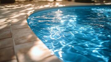 Clear blue water glistening in the evening sun beside a tranquil swimming pool photo