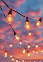 Colorful twilight sky with glowing light bulbs hanging above an outdoor setting photo