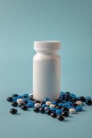 Prescription bottle surrounded by various colored pills on a blue background photo