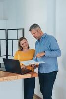Man and woman smiling professional business people talking using laptop computer working in office. photo