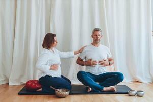Man and woman practicing mindful breathing together during a meditation session,seated on mats with sound bowls photo