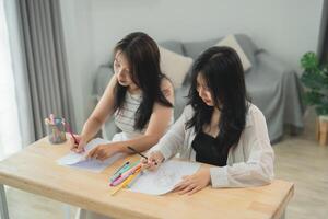 Two women sitting at a table drawing photo