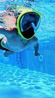 Underwater view of a child diving with mask in the pool. Young boy with mask on face swims in transparent water of a swimming pool. Vertical video