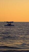 Catamaran on sea background at sunset. Men sailing in a blue catamaran on sea in the evening. Vertical video