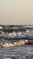 Storm in the sea. Big foamy waves crashing on the beach. Oceanic background at the edge of a coastline. Close-up. Vertical video