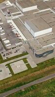 Modern exterior of industrial complex at daytime. Aerial view of manufacturing structure with parking for machinery outdoors. Vertical video
