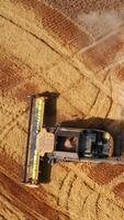 Powerful modern combine making turn in the field of wheat. Big machine leaving the curve trail in plantation. Aerial footage. Vertical video