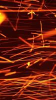 Red hot sparkles of fire flying horizontally at a very fast speed. Orange particles isolated on the black background. Vertical video