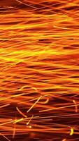 Lots of red hot sparkles alongside with white ones thrown at a very good speed. Bright ablaze particles at black backdrop. Vertical video
