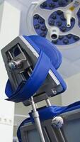 Folding chair with different appliances standing under the powerful lamp in dentist's cabinet. Close up. Low angle view. Blurred backdrop. Vertical video