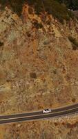 Wavy road through the mountains. Highway with place for stop to watch the nature and sightseeing. Sunny day background. Vertical video