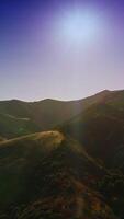 Amazing mountainous territory with no trees growing on. Drone rising over the mountains in the rays of bright sun. Vertical video