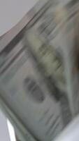 Hundred dollar bills falling on the holder in cash counting machine. Money counted machine stops working. Close up. Blurred backdrop. Vertical video