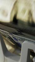 Rotating mechanism of cash machine turning money. One hundred dollar bills being counted in electronic device. Close up. Vertical video