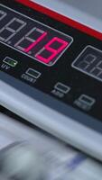 Electronic scoreboard of cash counting machine with numbers on. Dollar bills rotating in the device. Close up. Vertical video