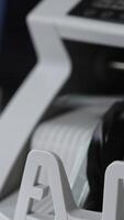 Switched on money counting machine. Hundred dollar bills turning in the counting mechanism. Close up. Vertical video
