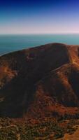 Stunning scenery of mountains locating near the ocean. Drone rising footage over the rocks at the backdrop of blue endless horizon. Vertical video
