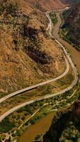 Rocky hills of amazing mountains in Colorado, USA. River flowing at the foot of mountain and roads passing along the river from aerial view. Vertical video