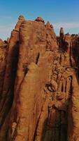 Flying around the weirdly shaped mountains with little greenery on top. Beautiful rocks at backdrop of blue skies. Vertical video