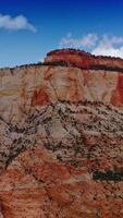 Wonderful huge rock with flat top and little greenery on. Amazing canyon of Zion National Park in Utah, USA at the backdrop of blue sky with white clouds. Vertical video