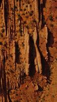 Car going by the road parallel to the oddly-shaped mountains. Dry orange landscape of desert in Utah, USA from aerial view. Vertical video