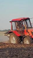 Red tractor in a field. Tractor ploughing a field with a trail of dust behind it video