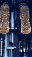 Cooking oil production. Plastic bottles filling with olive oil inside the modern factory. Automated machine moving on a circle way with refined oil. View from below. Vertical video