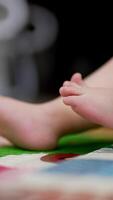 Caucasian child lies on back bent in knees. Close up of tiny baby feet moving slowly. Blurred backdrop. Vertical video