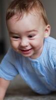 Adorable cheerful laughing toddler standing on all fours on the floor and swaying. Little kid playing with a toy. Vertical video
