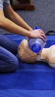 Training session for saving life. Instructor shows cardiac exercise on a mannequin. Demonstration of cpr on a dummy with breathing apparatus. Vertical video