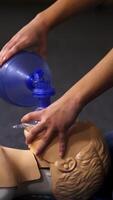 Teaching procedure on a dummy. Medical demonstration of resuscitation on a mannequin in training center. Instructor showing breathing exercise with medical apparatus. Vertical video