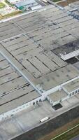 Industrial complex. Rooftops of industrial buildings with car parking on field. Large factory from above. Top view. Vertical video