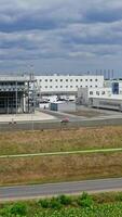 Exterior of modern factory. Large territory of industrial buildings on field under blue sky. Manufacture outdoors. Front view. Drone flight. Vertical video