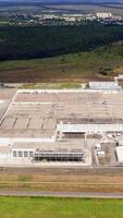 Large industrial territory in nature. Modern plant with car parking from above. Huge manufacturing in the countryside. Aerial view. Vertical video