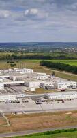 Industry on field. Large territory of industrial plant on green nature background under blue sky. Manufacturing in rural place. Aerial view. Vertical video