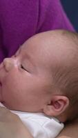 Little baby opens its mouth in hunger. Mother gives a bottle to her child, it suckles and milk drops appear on its cheek. Close up. Vertical video