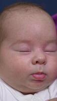 Sweet child sleeping tightly in his mom's hands. Caring momma trying to wake him up by touching little nose lovingly. Adorable sleeping newborn close up. Vertical video