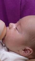 Loving mother holding a baby in her arms and feeding it from the bottle. Newborn child being fed from a bottle with pacifier. Close up. Vertical video