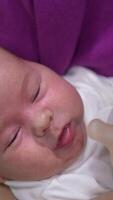 Adorable child in mother's hands ready to have meal. Little kid refuses to take the bottle first but then takes it and starts to eat. Close up. Vertical video