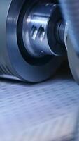 Conveyor line with special material for nappies manufacturing. Rotating rollers over the line of conveyor. Close up. Vertical video