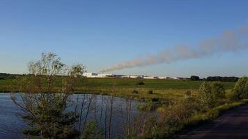 Factory In The Middle Farmland. Factory pipes polluting air on a green field video