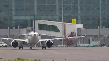 Airliner taxiing to terminal, rear view. An aircraft with an unrecognizable livery on the airfield video